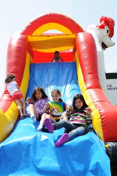 Children sliding down an inflatable water slide at a backyard party in Montgomery, TX